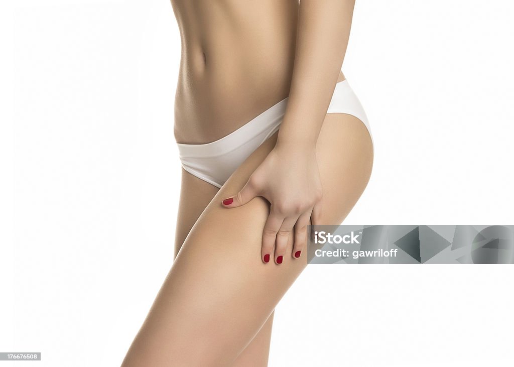 Female squeezing skin on her legs and showing no cellulite Female squeezing skin on her legs and showing no cellulite in her perfectly shaped body. Isolated on white background Adult Stock Photo