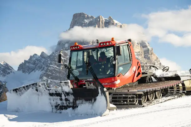 Piste groomer in front of the Dolomites alps Mountains, Italy. Snow groomer in dolomites alps in Italy.