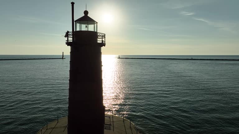 Three lighthouses framed against the sunlight splashed water.