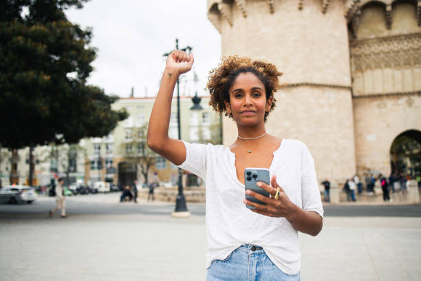 istock Latin woman raising hand and using smartphone 1766766892