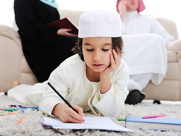 Muslim boy doing homework in front of parents stock photo