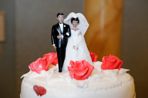 Ethnic Bride and groom decorate wedding cake
