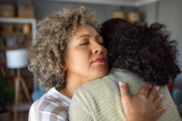 Don't worry, everything will be alright! Worried mid adult woman embracing her friend at home. mercy hug stock pictures, royalty-free photos & images