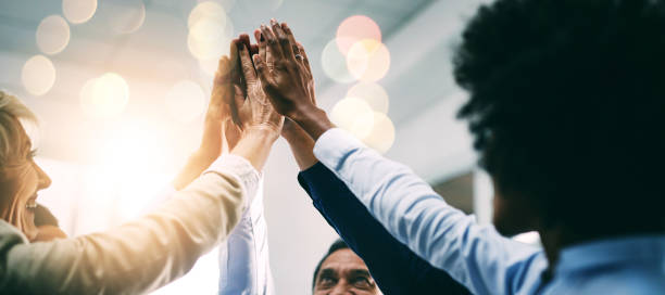 Closeup, high five and business people with support, hands and collaboration with mission, achievement or cooperation. Staff, group or corporate professionals with teamwork, bokeh or celebration