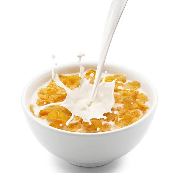 pouring milk into corn flakes creating splash