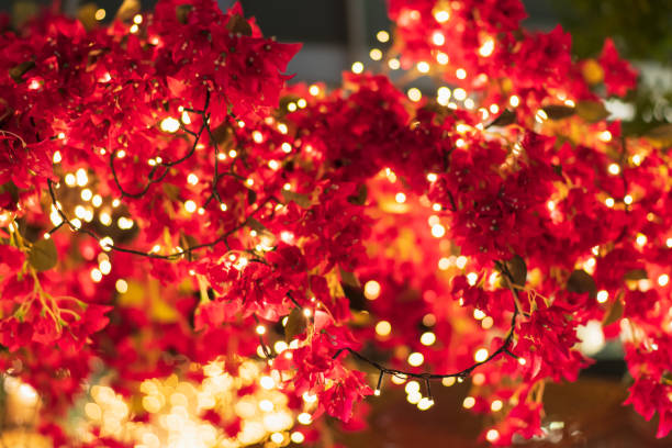 istock Glowing garland on a tree with red flowers. Low light photography. 1766844327