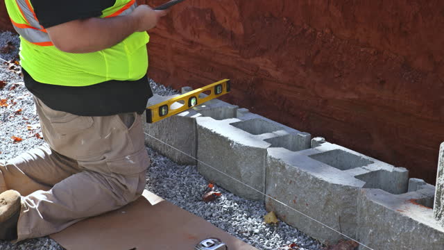 A construction worker was mounting concrete blocks to retaining wall on construction site