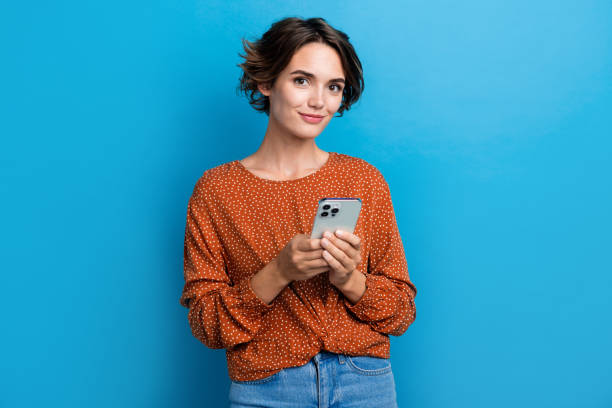 Photo portrait of attractive young woman hold device write comment dressed stylish brown clothes isolated on blue color background stock photo