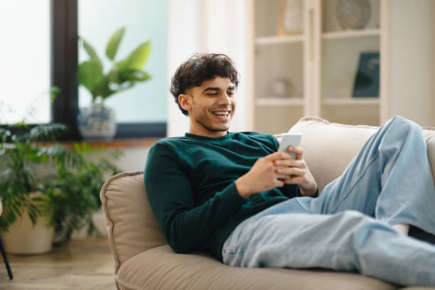 istock Arabic Man Using Phone Lying On Couch Relaxing At Home 1766860695