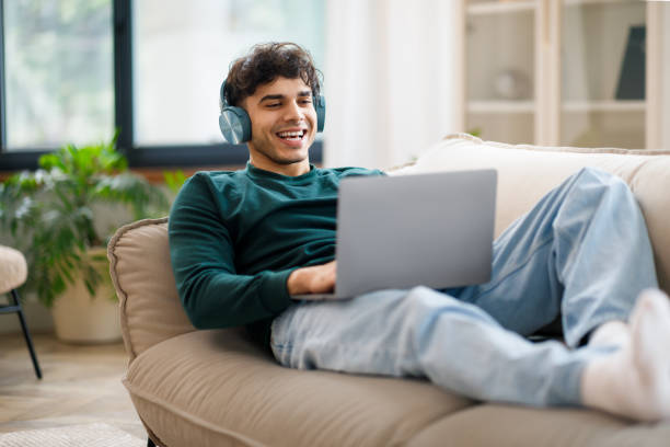 istock Smiling Arab Guy In Wireless Headphones Using Laptop At Home 1766860775
