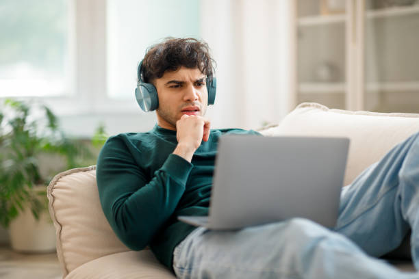 istock Displeased Arab Man In Headphones Using Laptop Having Problem Indoor 1766861333