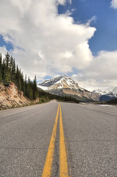 istock Double yellow road line with rocky mountain in background 176689784