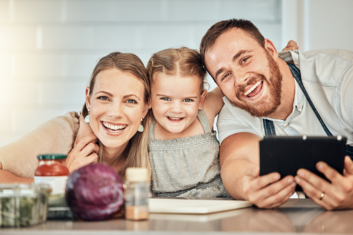 Happy family, cooking and parents with child in a kitchen to prepare a meal with online recipe in a home together. Bonding, smile and portrait of kid hug mother and father in a house with food