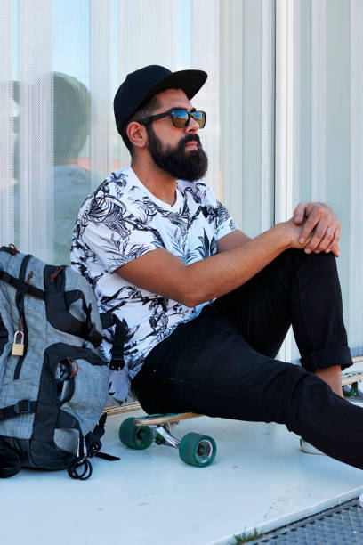 istock Bearded male skater sitting on longboard with backpack 1766911945