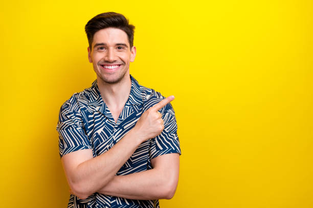 istock Photo of friendly satisfied young man beaming smile indicate finger empty space blank isolated on yellow color background 1766930022