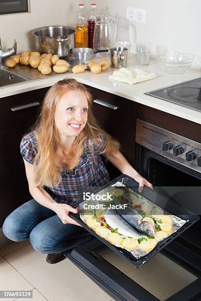 Felice Ragazza Cucinare Il Pesce Crudo In Forno - Fotografie stock e altre immagini di Adulto - Adulto, Alimentazione sana, Allegro