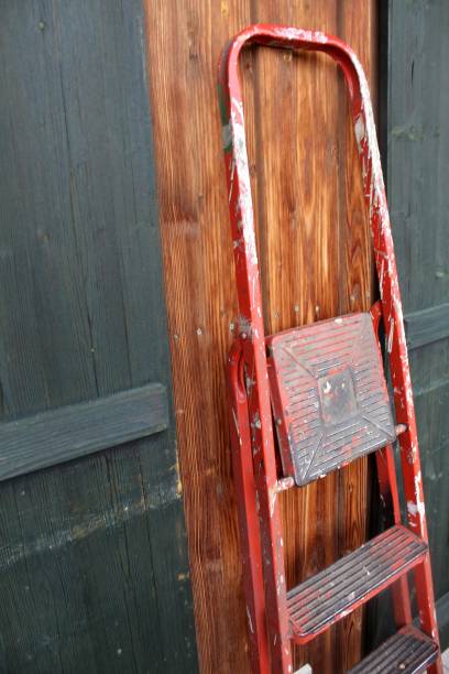 istock Old, red, dirty ladder, smeared with paint, leaning against wooden wall 1766947430