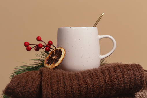 Cozy winter lifestyle concept. Cup of hot drink with warm knitted clothes.