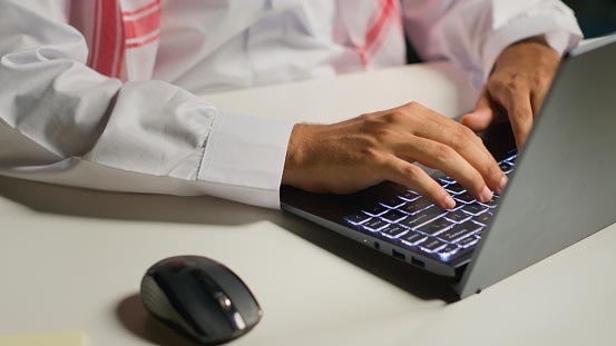 Close up shot of businessman using laptop and mouse in office to solve various work tasks. Employee typing on notepad keyboard in order to deliver finalized project paperwork to management