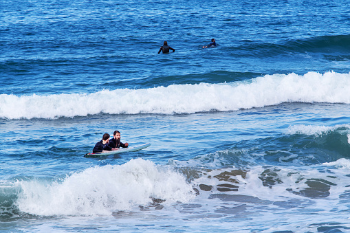 12-24-2014 Tel Aviv, Israel. 2 bearded men holding on on to one board - maybe one teacher? at coastline of sunny Tel Aviv during Christmas week