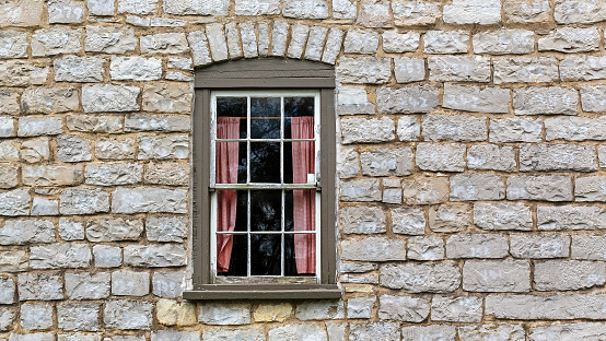 Window on an old wall with growing plant