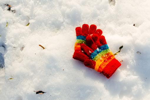 Child’s mitten forgotten on the snow, after kids play in snowy forest