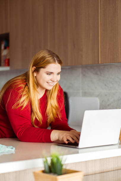 istock Smiling woman working at home, in stylish kitchen using laptop, copywriter typing, looking at camera 1766983286