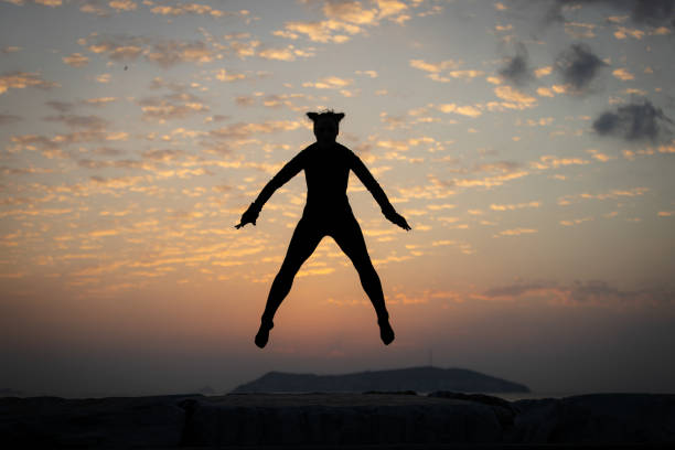 Young woman is exercising in over by the sea at sunset.