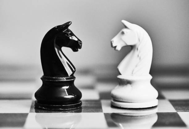 istock Conflict and rivalry: black and white chess knights face off against each other 1767024702