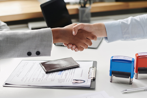 Close-up of people shaking hands during meeting in visa agency