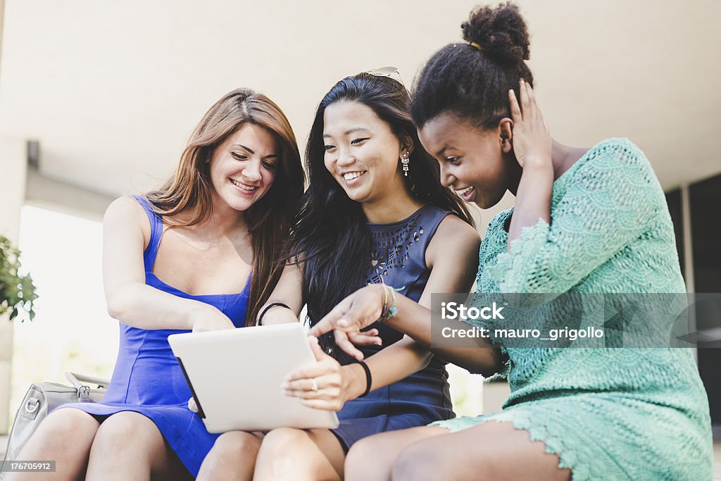 Tres mujeres jóvenes mediante el uso de una tableta digital - Foto de stock de 18-19 años libre de derechos