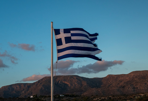 Flag of Greece on the pole in the sky at sunset