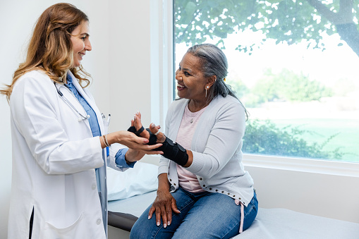 While at the clinic today, the mature female patient smiles while talking to her orthopedic surgeon about how she has been feeling.