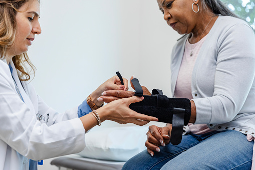 The female orthopedist fits her patient with a wrist splint after she sustained an injury.