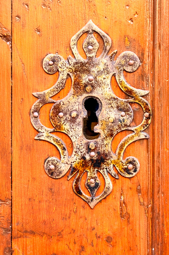 Artful door knocker with face and ring on a reddish-brown wooden door in Cartagena, Colombia, Unesco World Heritage