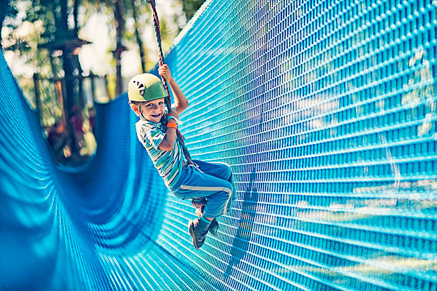 Little boy zipping in adventure park Little boy zipping on zip line in outdoors amusement park. canopy tour photos stock pictures, royalty-free photos & images