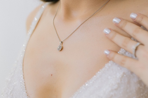 A beautiful woman wearing a white bridal gown with a delicate necklace