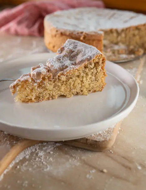 Homemade fluffy almond cake baked without flour. Served sliced on rustic and wooden table background.