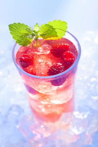 cold refreshment with raspberries, mint and soda on ice cubes.