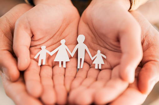 Paper cutout, family and hands of people together for security, adoption or foster care. Zoom of parents and children figure in palm for love, art or support for health insurance, charity or wellness