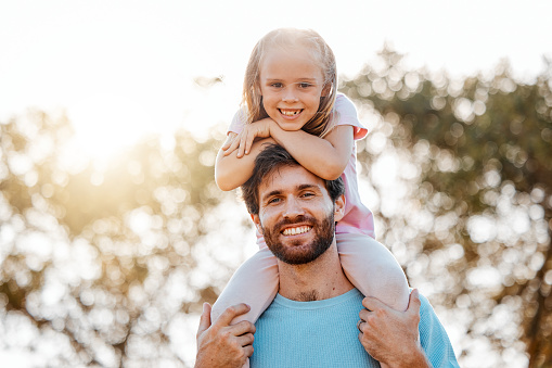 Nature, happy and portrait of father with child in an outdoor park playing, bonding and having fun. Happiness, smile and girl kid on the shoulder of young dad from Australia in garden together.
