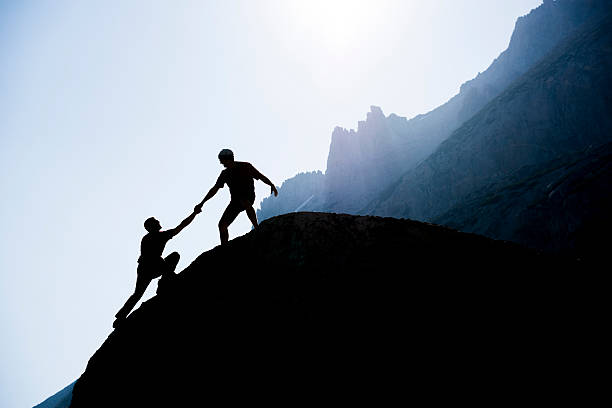 istock Two climbers reaching the top of a mountain 176710075