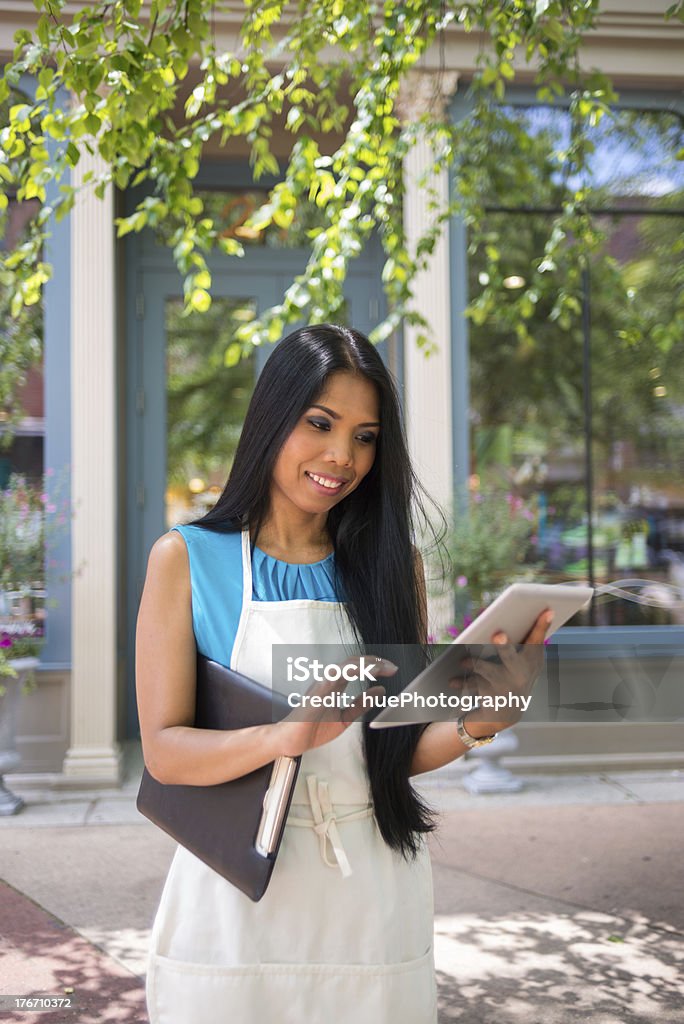 Small Business Owner Asian woman working on a tablet outside of her store front. Adult Stock Photo
