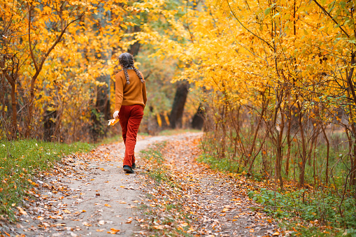 Sweet little boy playing at the park throwing the autumn leafs very happy