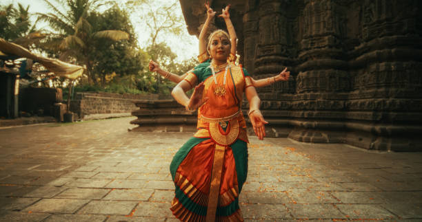 porträt indischer frauen in traditioneller kleidung, die bharatanatyam im bunten sari tanzen. drei ausdrucksstarke junge frauen führen eine volkstanz-choreografie in einem alten tempel auf - bharatanatyam stock-fotos und bilder