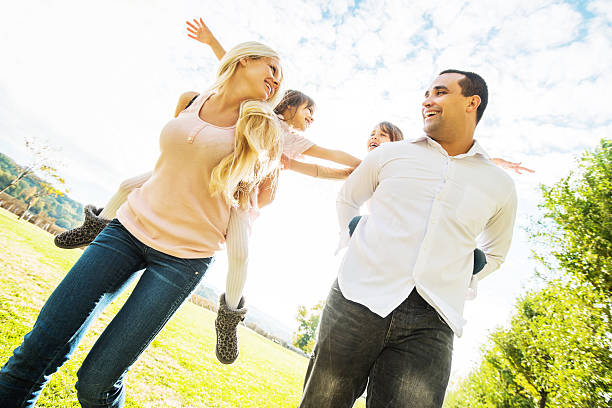 istock Mother and father piggybacking their daughters against sky. 176712650