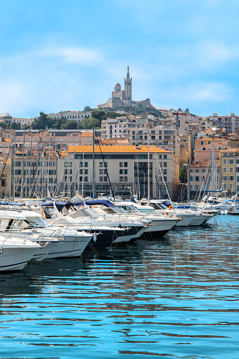 The Old Port of Marseille. Yachts and boats moored in the marina. Cathedral high on a hill overlooking the city in the background. Cote d Azur, South of France, Europe. Colorful travel image on a summer day.