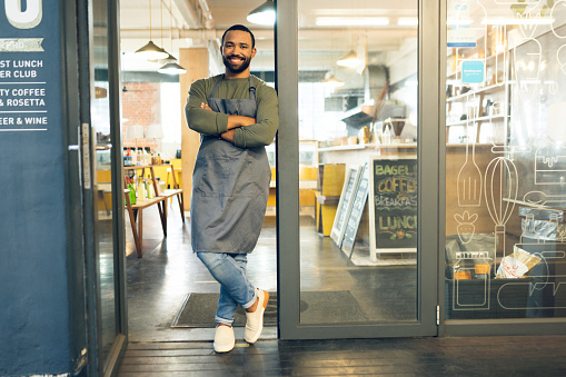 Happy man, portrait and small business owner on door of cafe with arms crossed in confidence or retail management. Male person, barista or waiter smile by entrance of coffee shop or ready for service