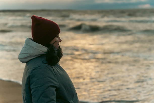 istock a woman stands on the seashore in the cold during a storm. 1767145689