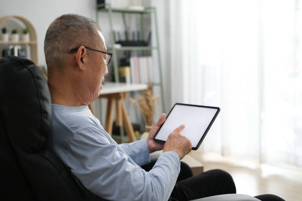 istock Senior Asian men at the sofa couch using smartphone tablet for browsing internet and reading news online in the morning. 1767165827